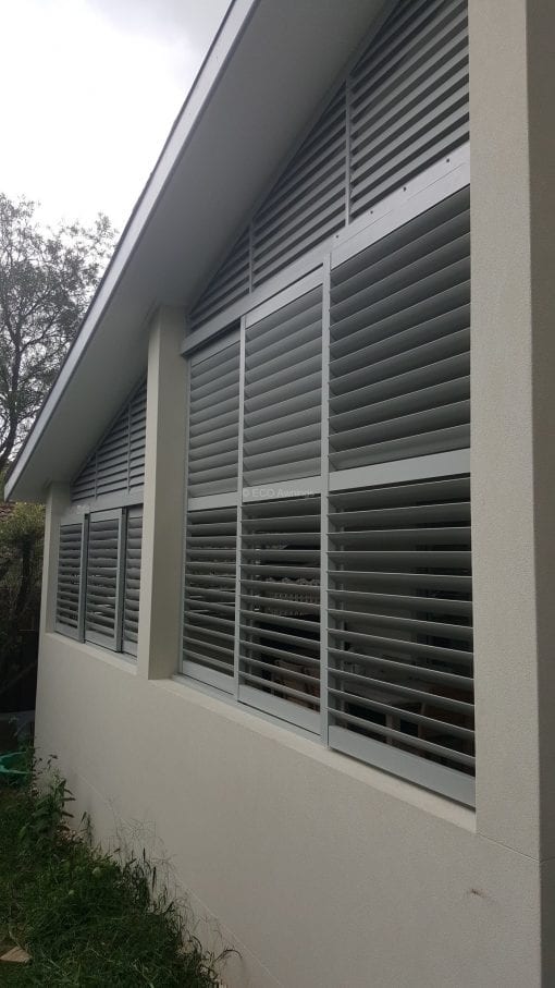 Privacy screen with sliding adjustable blades with a fixed blade above on a angle